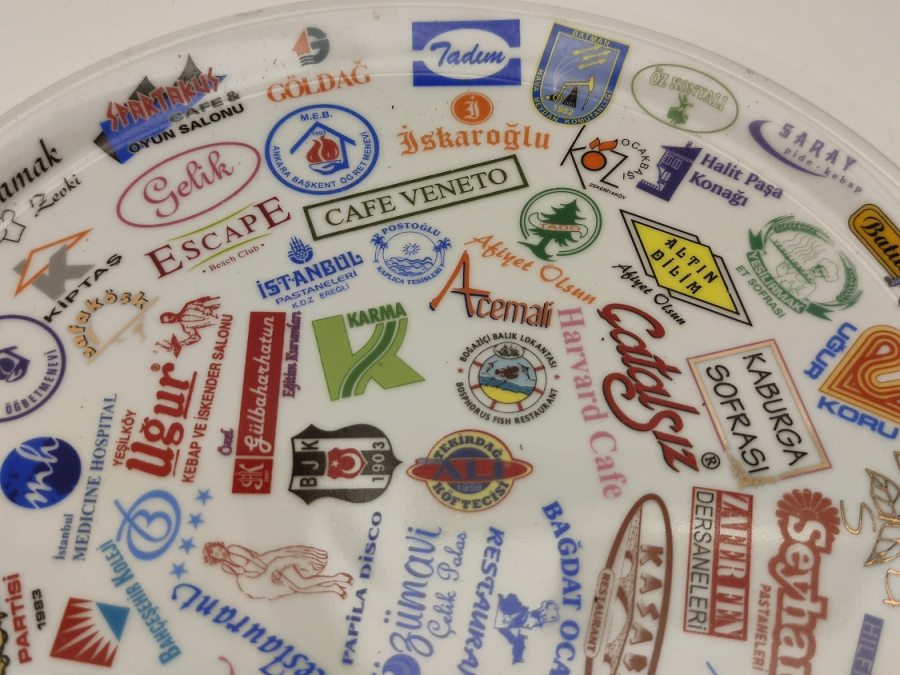 NECMİ SANATCI İMZALI KANADA DAMGALI ÜZERİNDE BİRCOK TANINMIŞ MARKA LOGOLARI BASKILI PORSELEN TABAK