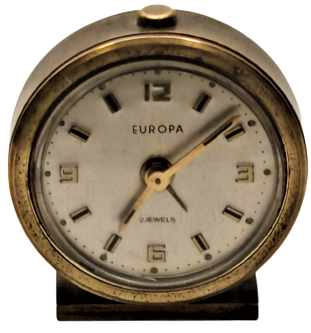 1930 EUROPA  2 JEWELS KURMALI SAAT MEKANİK PİRİNC UFAK BOYDA CALARLI BAŞUCU SAATİ SORUNSUZDUR